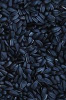 A pattern of many unprocessed fried sunflower seeds in a black shell. photo