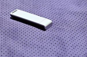 A modern portable USB wi-fi adapter is placed on the violet sportswear made of polyester nylon fiber photo