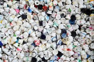 A large number of caps from cans of aerosol paint for graffiti. Smeared with colored paint nozzles lie in a huge pile photo