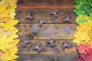 Several spinners among the many yellowing fallen autumn leaves on the background surface of natural wooden boards of dark brown color photo