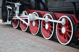 ruedas de la vieja locomotora de vapor negra de la época soviética. el lado de la locomotora con elementos de la tecnología giratoria de trenes antiguos foto