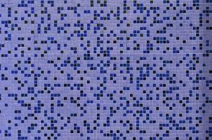 The texture of the wall, decorated with a mosaic of various small square tiles. Abstract pattern of ceramic tiles on the wall photo