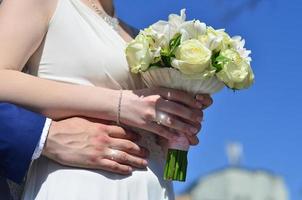 The newlywed couple is holding a beautiful wedding bouquet. Classical wedding photography, symbolizing unity, love and the creation of a new family photo