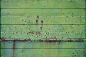 Texture of an old green metal wall with significant damage from exposure to unfavorable weather conditions and dampness photo