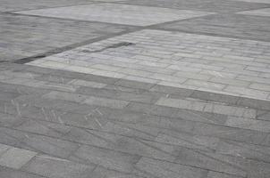The texture of granite paving tiles from a variety of square shaped platforms under bright sunlight photo
