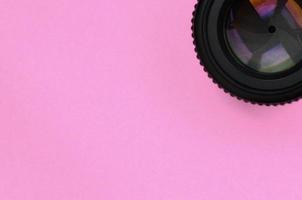 lente de cámara con apertura cerrada sobre fondo de textura de papel de color rosa pastel de moda en concepto mínimo foto