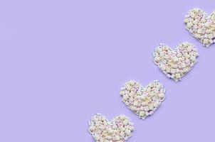 Colorful marshmallow laid out on violet and pink paper background. pastel creative textured hearts. minimal photo