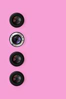 A few camera lenses with a closed aperture lie on texture background of fashion pastel pink color paper in minimal concept. Abstract trendy pattern photo