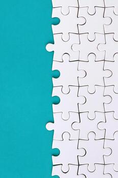 Fragment of a folded white jigsaw puzzle on the background of a blue plastic surface. Texture photo with copy space for text