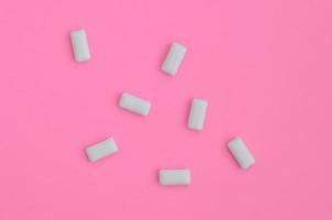 unos cuantos chicles se encuentran en el fondo de textura del papel de color rosa pastel de moda en un concepto mínimo foto