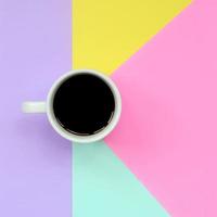 Small white coffee cup on texture background of fashion pastel blue, yellow, violet and pink colors paper in minimal concept photo