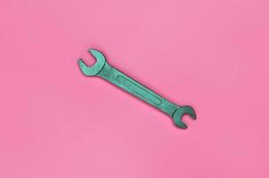 Metallic spanner lie on texture background of fashion pastel pink color paper in minimal concept photo