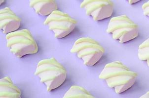 Colorful marshmallow laid out on violet paper background. pastel creative textured pattern. Perspective macro shot photo