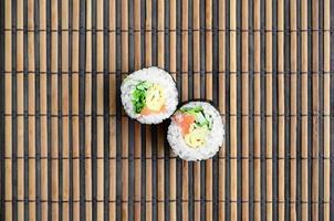 Sushi rolls lies on a bamboo straw serwing mat. Traditional Asian food. Top view. Flat lay minimalism shot with copy space photo