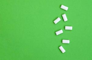 A few chewing gums lie on texture background of fashion pastel green color paper in minimal concept photo