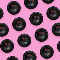 A few camera lenses with a closed aperture lie on texture background of fashion pastel pink color paper in minimal concept. Abstract trendy pattern photo