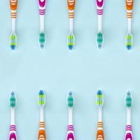 A lot of toothbrushes lie on a pastel blue background. Top view, flat lay. Minimal concept photo