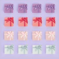 montones de pequeñas cajas de regalo de colores con cintas se encuentran sobre un fondo violeta. minimalismo plano vista superior patrón foto