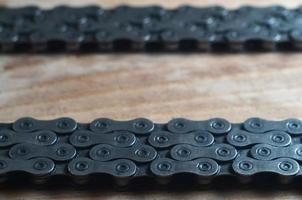 Dirty and oily chain from a mountain bike lying on a wooden table in a bicycle shop photo