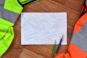 A crumpled sheet of paper with two pencils surrounded by green a photo