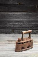 The heavy and rusty old coal iron lies on a wooden surface photo