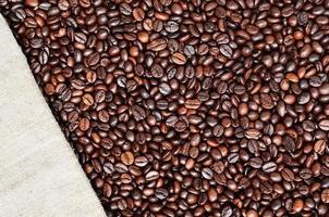 Texture of a gray canvas made of old and coarse burlap with coffee beans on it photo