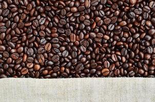 Texture of a gray canvas made of old and coarse burlap with coffee beans on it photo