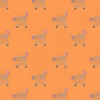 Shopping addiction, shopping lover or shopaholic concept. Many small empty shopping carts perform a pattern on a pastel colored paper background. Flat lay composition, top view photo