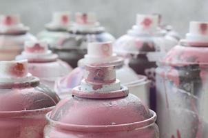 A lot of dirty and used aerosol cans of bright pink paint. Macro photograph with shallow depth of field. Selective focus on the spray nozzle photo