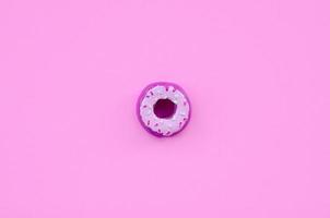 Single small plastic donut lies on a pastel colorful background. Flat lay minimal composition. Top view photo