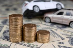 Toy car in accident on a background of 100 dollar bills and stacks of golden coins photo