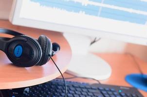Big black headphones lie on the wooden desktop of the sound designer photo
