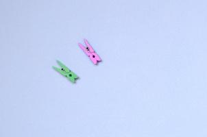 Two colored wooden pegs lie on texture background of fashion pastel violet color paper photo
