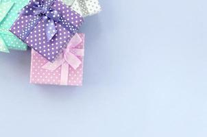 Pile of a small colored gift boxes with ribbons lies on a violet background photo