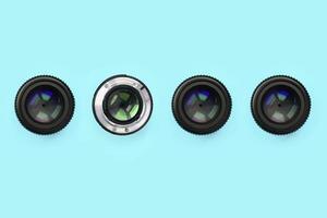 A few camera lenses with a closed aperture lie on texture background of fashion pastel blue color paper photo