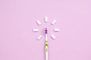 Toothbrush and chewing gums lie on a pastel pink background photo