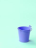 A miniature empty lilac bucket lies on a green pastel background photo