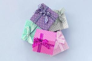 Pile of a small colored gift boxes with ribbons lies on a violet background photo