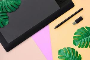 Graphic tablet and pen, memory card and monstera leafs photo