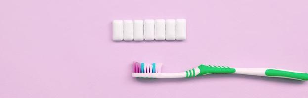 Toothbrush and chewing gums lie on a pastel pink background photo