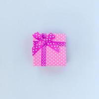 Small purple gift box with ribbon lies on a violet background photo