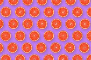 Pattern of grapefruit citrus slices on bright purple background photo