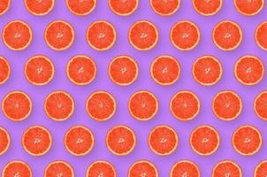 Pattern of grapefruit citrus slices on bright purple background photo