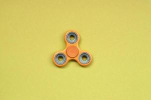 orange fidget spinner lies on texture background of fashion pastel orange color paper photo