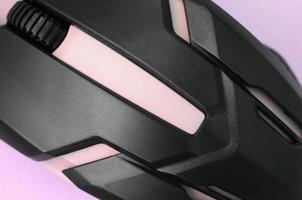 Closeup of a black gaming optical mouse on a pink background photo