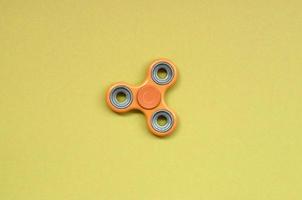 orange fidget spinner lies on texture background of fashion pastel orange color paper photo