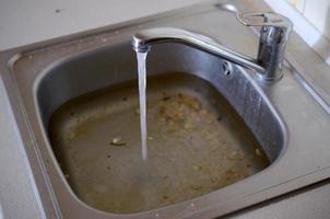 Stainless steel sink plug hole close up full of water and particles of food photo