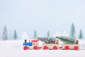 árbol de navidad en tren de juguete corría a través de la nieve en el campo de fondo de paisaje natural foto