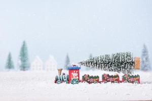 árbol de navidad en tren de juguete corría a través de la nieve en el campo de fondo de paisaje natural foto