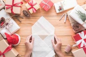 Hand are wrapping gifts of the Merry Christmas and Happy New Year decoration for celebration on wood background with copy space photo
